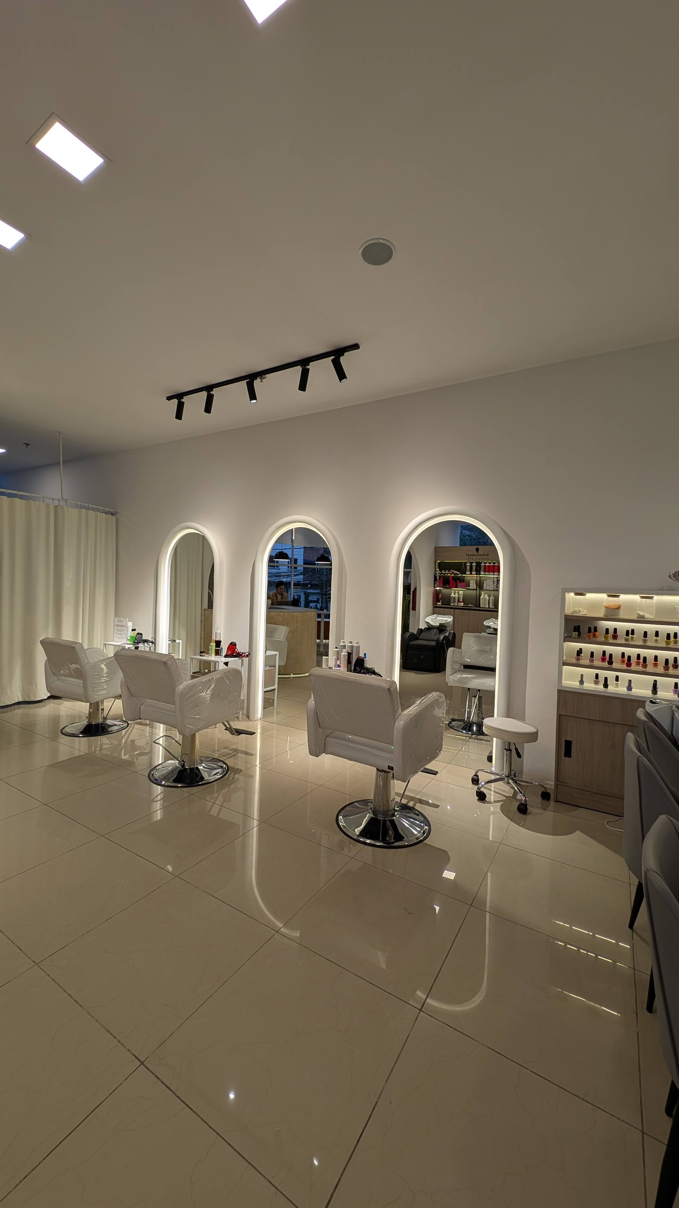 Salon principal BRACA Hair Lab con sillones blancos y espejos arqueados con iluminacion LED