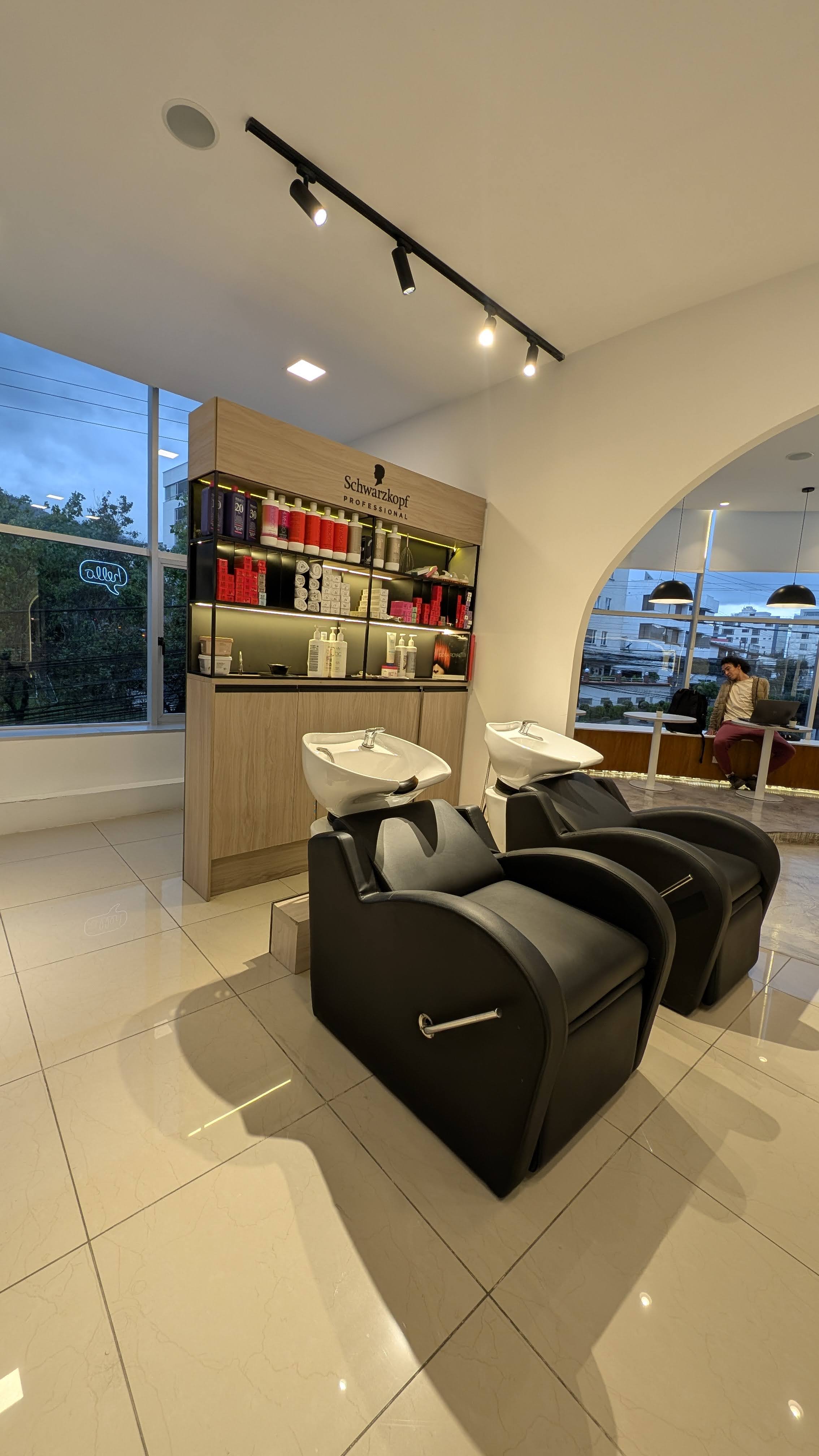 Area de lavado de cabello con sillones reclinables negros y productos Schwarzkopf Professional